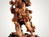 a wooden statue of a man holding a bird on a rock