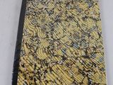 un gros plan d'un cahier jaune et noir posé sur une surface blanche