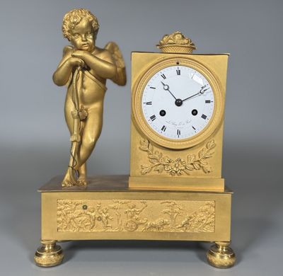 une horloge en or surmontée d'une statuette représentant un Cupidon