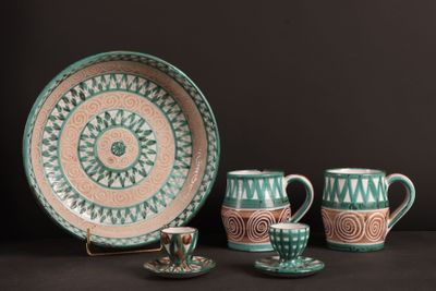 trois tasses, une soucoupe et une assiette posées sur une table