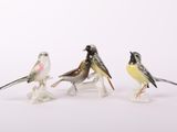 trois petites figurines d'oiseaux posées sur une surface blanche
