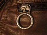 the zipper of a brown leather jacket with a metal ring on it