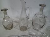 trois vases en verre posés sur une table à côté d'une assiette