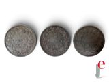 three silver coins sitting on top of each other on a white surface