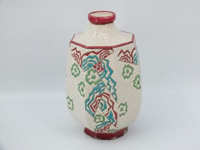un vase blanc avec une anse rouge et un motif