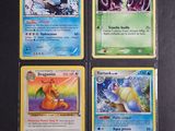quatre cartes Pokémon différentes posées sur une table noire
