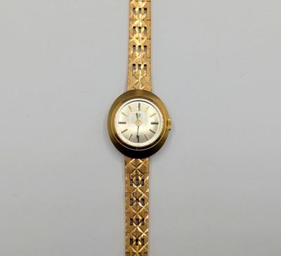 a gold wrist watch with a white face on a white surface