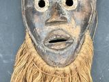 a close up of a mask with long hair on a black surface