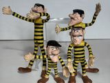 trois figurines représentant un groupe d'hommes vêtus de vêtements rayés