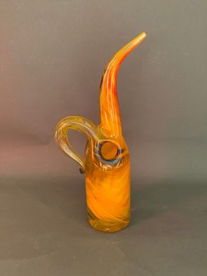 un vase en verre jaune muni d'une anse incurvée, posé sur une surface grise