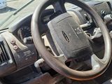 a steering wheel and dashboard of a truck in a parking lot