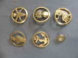 several gold metal buttons with various designs on them on a table
