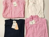 three shirts with tags on them are sitting on a table