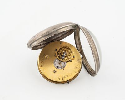 une vieille montre de poche posée sur une surface blanche