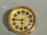 a gold clock with roman numerals on the face