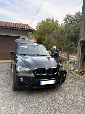 un SUV BMW noir garé devant un garage