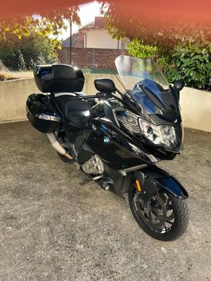 a black motorcycle parked in a parking lot next to a fence