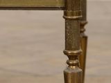 a gold metal table with a glass top on a wooden floor