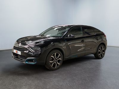 Une voiture noire est garée dans une pièce aux murs blancs.