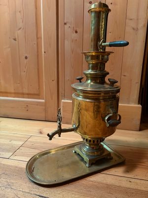a brass coffee grinder sitting on a wooden floor