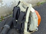 a blower and a backpack on the ground next to a wall