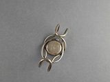 silver plated pendant with a leaf and a coin in the middle