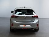 the back end of a silver car in a room with a white wall