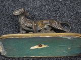 a bronze dog that is laying down on the ground