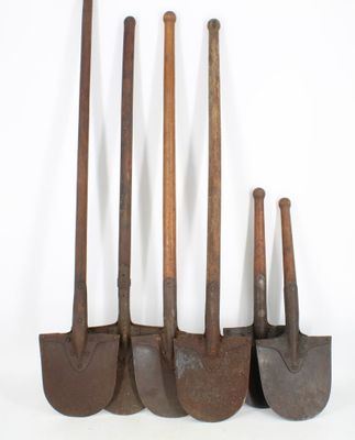 several old rusty shovels are lined up against a white background
