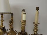 three brass candles and a lamp on a white surface