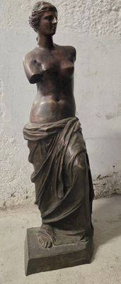 une statue représentant une femme debout devant un mur