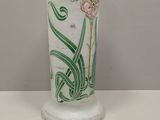 a glass vase with flowers painted on it sitting on a table