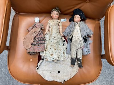 two dolls that are sitting on top of a chair
