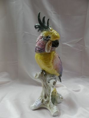 une figurine représentant un perroquet jaune et rose perché sur une branche