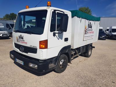 un camion blanc avec un auvent vert garé sur un parking