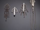 three silver brooches with chains and chains hanging from them