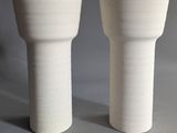 two white vases sitting next to each other on a table