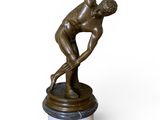 statue en bronze représentant un homme tenant un frisbee, posée sur un socle en marbre