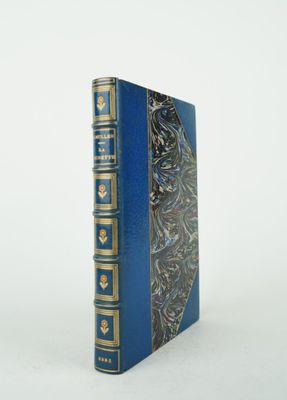 un vieux livre bleu aux bords dorés posé sur une surface blanche