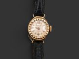 a gold plated wrist watch with a black leather strap
