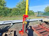 un poteau rouge et jaune posé par terre à côté d'un tas de bois