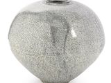 un vase gris posé sur une surface blanche