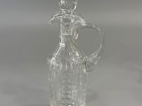 a clear glass bottle with a handle on a table