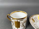 a cup and saucer sitting on a table next to each other