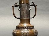 a bronze vase with two birds on the handle