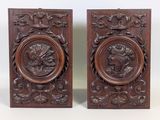 pair of carved wood plaques depicting a man and a woman