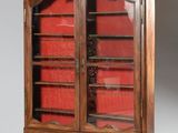 une vieille armoire en bois avec une porte en verre rouge