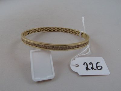 a gold bracelet and a cell phone on a white table