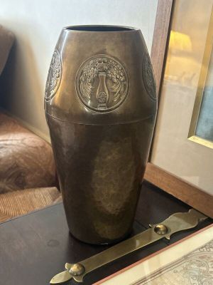 an antique brass vase on a table next to a framed picture