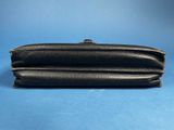 a black leather purse sitting on top of a blue surface